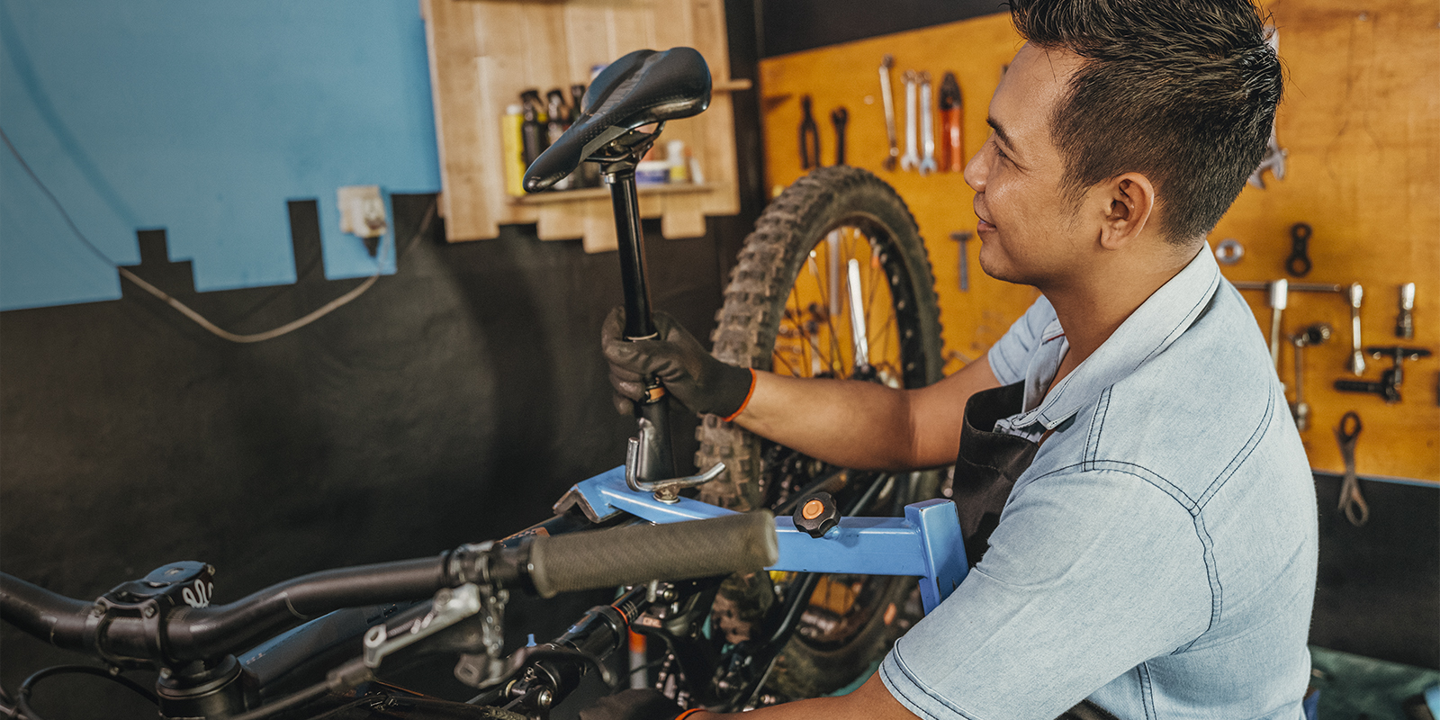 A man assembles a saddle on a bicycle frame in a workshop